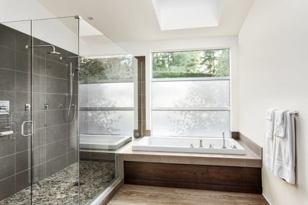 Large furnished bathroom in luxury home with tile floor, fancy cabinets, large mirror, and bathtub